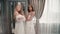Woman fashion models pose for camera, wear wedding dress. Friends two women at boutique store.