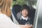 Woman fastening child with safety seat belt in car