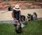 Woman in fedora and sarong sitting on sidewalk surrounded with dusky monkeys