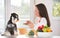 Woman feeding dog at kitchen table