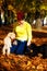 Woman feeds poodle in a beautiful autumn park.