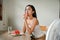 A woman feeling discomfort from the hot weather, eats watermelon and sits in front of a fan