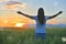 Woman feeling free in a beautiful natural setting, in what field at sunset