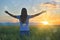 Woman feeling free in a beautiful natural setting, in what field at sunset