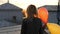 Woman feeling happy walking with balloon on rooftop. Back view.