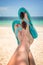 Woman feet with blue flip flops and sunglasses, beach and sea