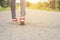 Woman feet with red sneaker shoes walking on the roadside.