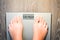 Woman feet stepping on a weight scale having problems with her diet