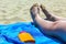 Woman feet and sunscreen tube on blue beach blanket