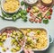 Woman female hands cooking pasta casserole with roasted romanesco cabbage and ham in creamy sauce on kitchen table background with