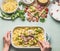 Woman female hands with spoon cooking pasta casserole with romanesco cabbage and ham in creamy sauce on kitchen table background w