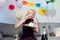 Woman in festive dress and party cap eating birthday cake with her hands, her face stained cream. A woman stuffing her