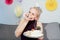 Woman in festive dress and party cap eating birthday cake with her hands, her face stained cream. A woman stuffing her