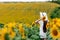 Woman in the field of sunflowers. A happy, beautiful young girl in a white hat is standing in a large field of sunflowers. Summer