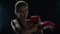 Woman fighter preparing for sport workout in dark gym. Portrait of woman boxer