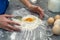 woman is fighting in the kitchen breaking eggs into flour and kneading dough into dumplings.