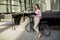 Woman with files in the hands standing outdoor in front of electric bike