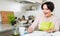 Woman filling banking documents and smiling in kitchen