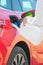 Woman filling a diesel engine fluid from canister into the tank of red car on the background of wind turbines. Reduction