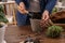 Woman filling flowerpot with soil at wooden table indoors, closeup. Transplanting houseplants