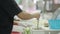 Woman fills a jar of green sauce at a street market in Bangkok