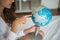 Woman finger point to on the world map globe ball model