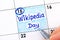 Woman fingers with pen writing reminder Wikipedia Day in calendar