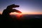 Woman fingers pick beautiful sun in natural twilight of sunset on the mountain