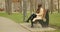 Woman finishing reading a book on bench stands up and leaving autumn park wearing brown mackintosh and scarf with hat.