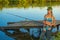 Woman fisherman in a swimsuit catches fish with a fishing rod at the pier from the shore