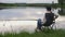 Woman with a fishing rod sitting on a chair by the lake