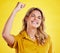 Woman, fist celebration and happy in studio for winning, goals and success for achievement by yellow background. Girl