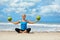 Woman fitness exercise with green coconuts on ocean beach