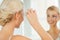 Woman fixing makeup with cotton swab at bathroom