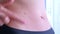 Woman flaking removing burnt skin on tummy after exposing too much to the sun.