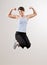 Woman flexing biceps while jumping in mid-air
