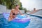 Woman floating on beach mattress in the blue outdoor pool. Summer holiday idyllic