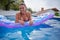 Woman floating on beach mattress in the blue outdoor pool. Summer holiday idyllic