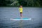 A woman is floating on a SUP board along a large river. Stand on the paddle boarding - amazing outdoor activities