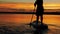 A woman floats on a sappboard in the evening in golden highlights from the sunset