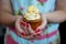 Woman in Floral dress with painted nails holding popcorn cupcake