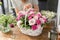 Woman florist create flower arrangement in a wicker basket. Beautiful bouquet of mixed flowers. Floral shop concept