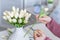 Woman florist cutting stem of tulips flowers with scissors and putting in vase on coffee table. Composing bouque.