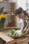 A woman florist in glasses and an apron works behind the counter in a flower shop