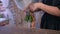 Woman florist packaging bouquet of roses in paper in flower shop, hands closeup.