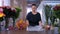 Woman florist works cuts paper sheet to pack flower bouquet in floristic shop.