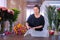 Woman florist works cuts paper sheet to pack flower bouquet in floristic shop.