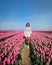 Woman in flower field, young girl in tulip field in the Netherlands during spring season on a bright sunny day