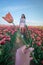 Woman in flower field, young girl in tulip field in the Netherlands during spring season on a bright sunny day