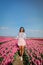 Woman in flower field, young girl in tulip field in the Netherlands during spring season on a bright sunny day